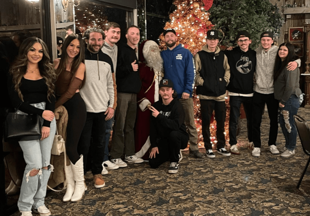 A group of people standing in front of a christmas tree.